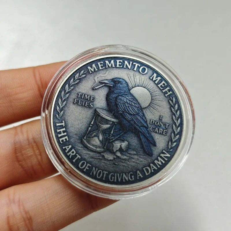A round, dark blue challenge coin featuring a silhouette of a crow and skull with text around the edge.