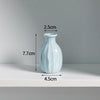 A light blue ceramic mini vase with a narrow neck and rounded body, shown against a white background.