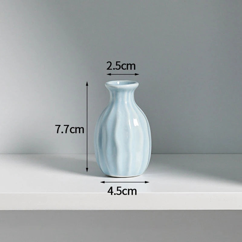 A light blue ceramic mini vase with a narrow neck and rounded body, shown against a white background.
