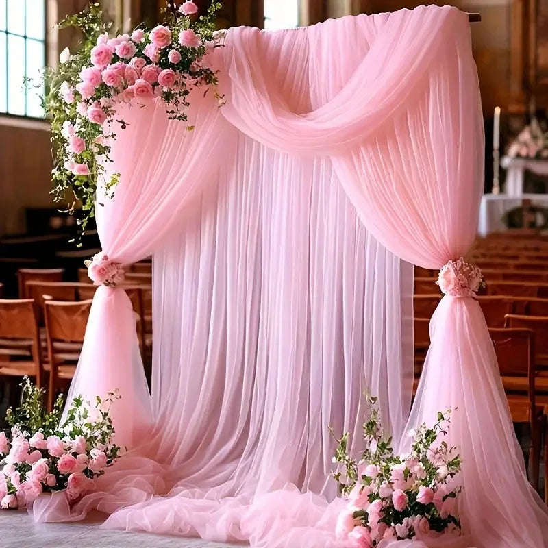 Tela rosa transparente que cae formando un telón de fondo con detalles florales para un evento.