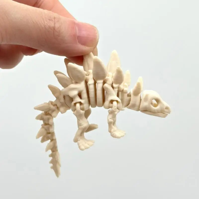 A hand holds a light beige 3D printed dinosaur skeleton model for desktop display.
