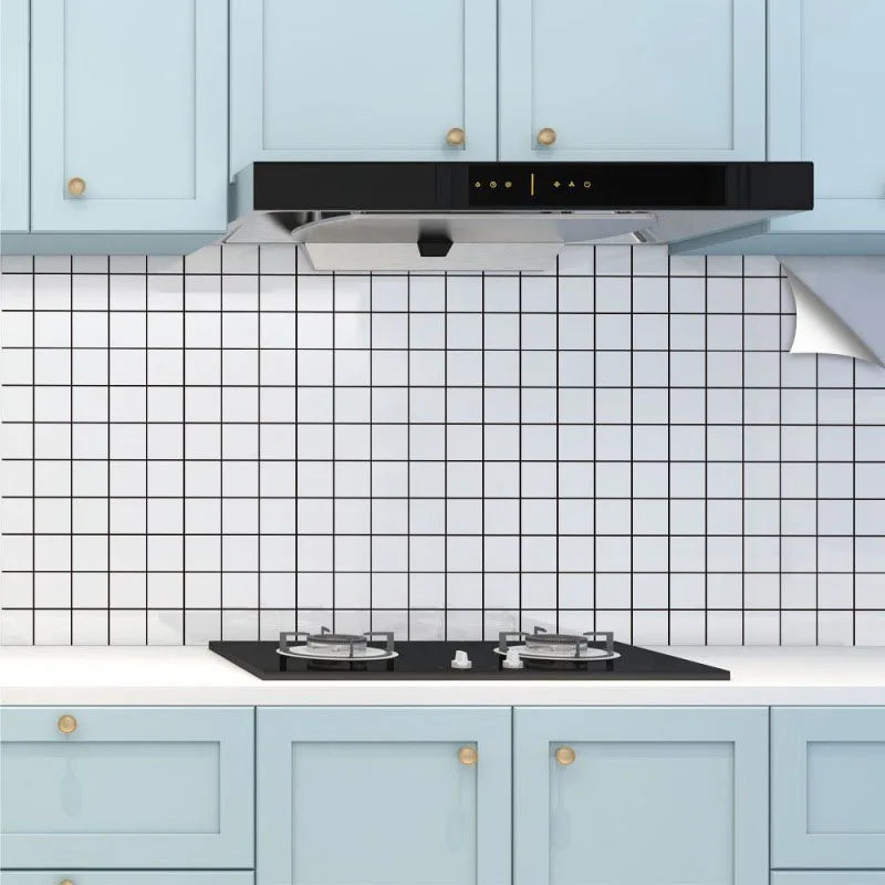 A kitchen featuring light blue cabinets, a black range hood, and a white subway tile backsplash.