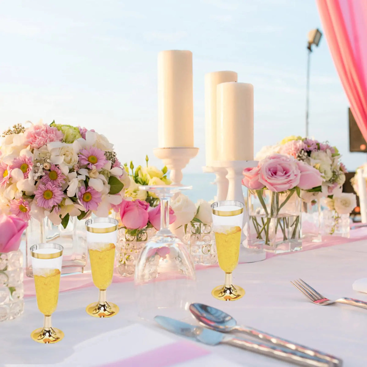 A display of elegant disposable plastic champagne flutes filled with yellow liquid on a white table.