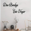Schwarzer Schriftzug an einer weißen Wand, der 'Dios Bendiga Este Hogar' mit dekorativen Ästen und Keramik zeigt.