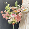Handmade crochet flower bouquet featuring pink, peach, and cream flowers on a green stem.