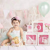 Pink and white balloon boxes with the letter O N E for first birthday decorations