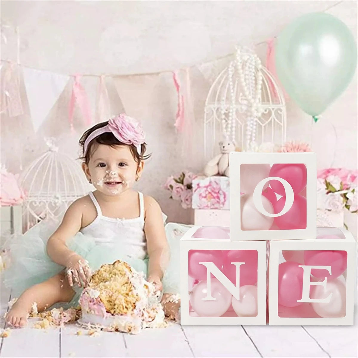 Pink and white balloon boxes with the letter O N E for first birthday decorations