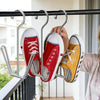 A hand hangs a pair of red and white sneakers on a stainless steel hanging shoe organizer rack.