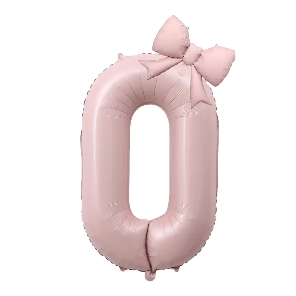 A large pink foil number balloon shaped like the digit zero with a bow.