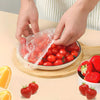 Hände legen wiederverwendbare Einweg-Essertöpfe über eine Schale mit frischen Tomaten und Erdbeeren.