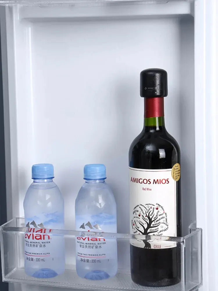 A glass shelf displays two clear plastic water bottles and a dark wine bottle labeled Amigos Mios