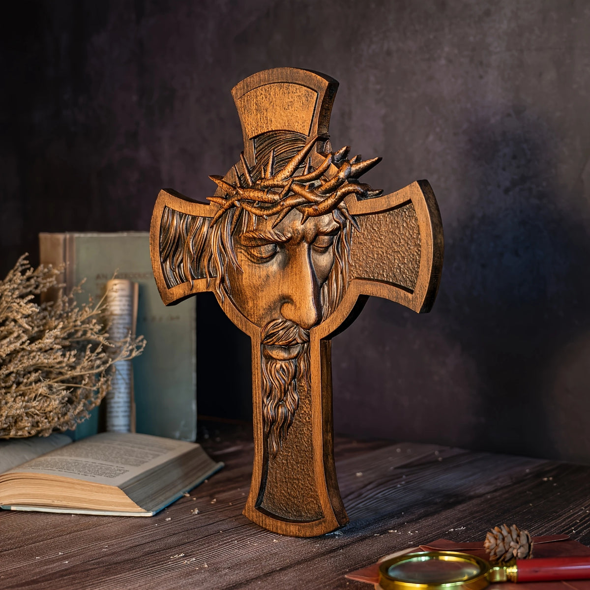 A wooden cross with a crown of thorns carved into the figure, displayed on a dark surface.
