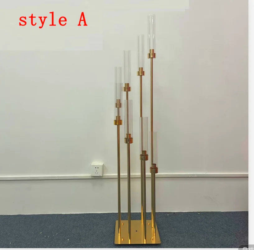 A tall gold metal candelabra set with eight glass candle holders displayed against a white wall.