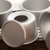 A set of five non-stick round cake molds with removable bases arranged on a wire rack.