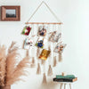 A macrame photo display hangs on a white wall, featuring multiple framed photos suspended by twine.