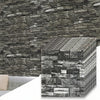 A close-up view of stacked 3D foam brick wallpaper panels in gray and black tones.