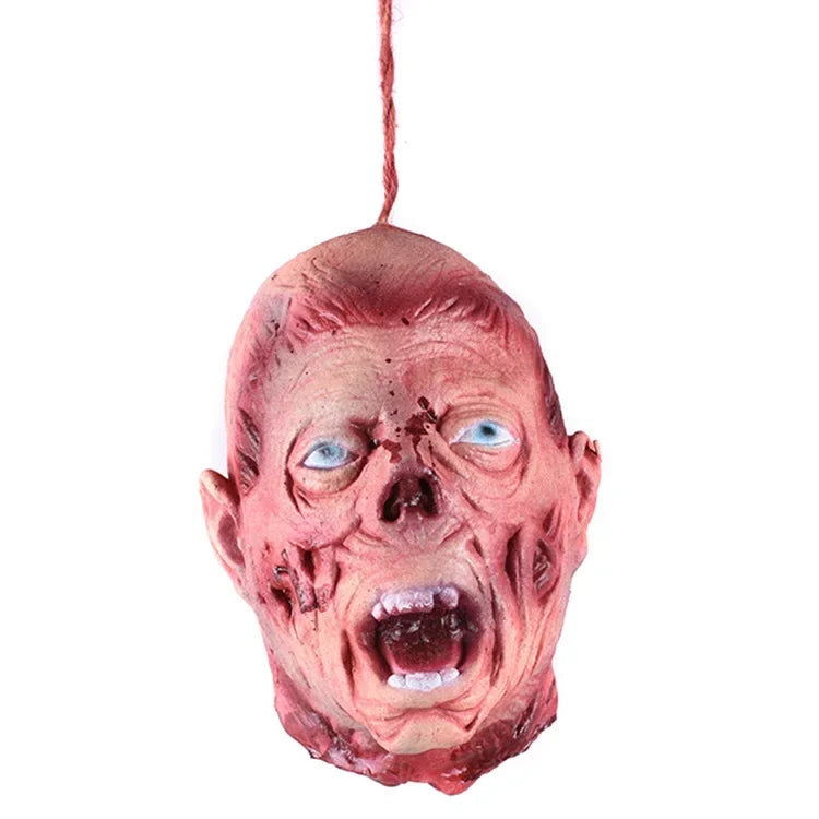 A realistic prop of a screaming, aged face with blue eyes and visible wounds, hanging by a string.