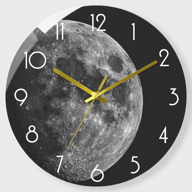 A black and white photograph of the moon face on a modern glass wall clock with gold hands.