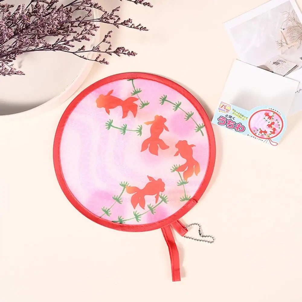 Pink fabric fan with orange silhouette designs for portable cooling