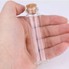 A hand holds a clear glass bottle with a cork stopper, used for crafts and storage.