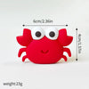 A red ocean animal cake topper featuring a whale, octopus, or turtle design with large white eyes.