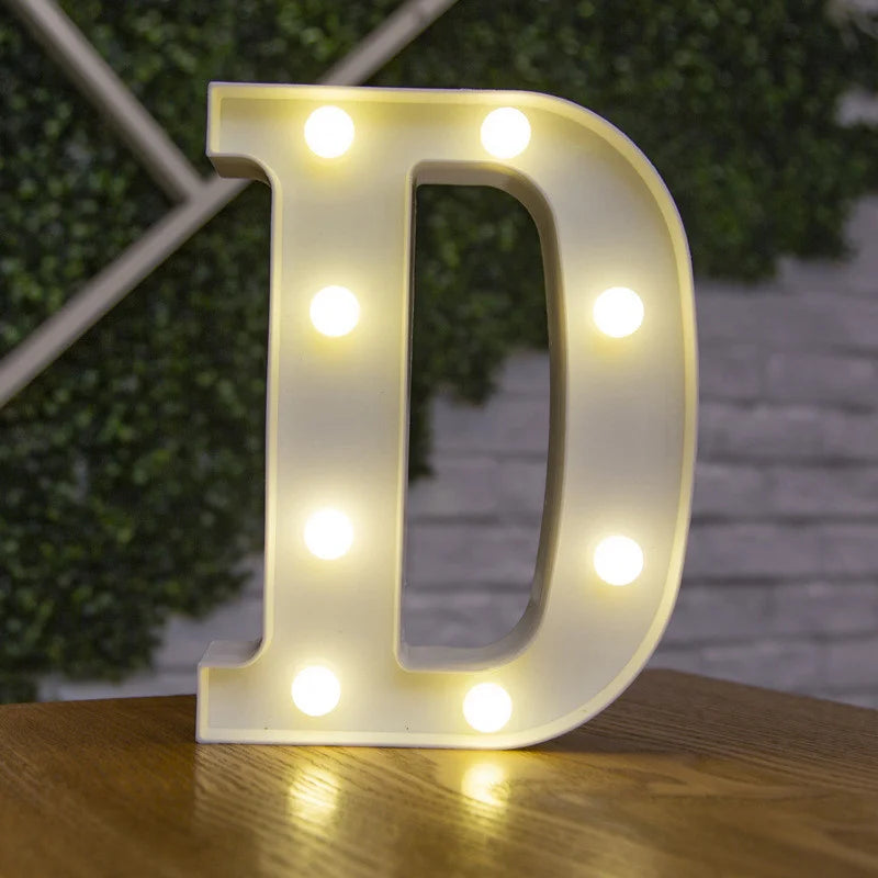 A glowing white alphabet letter D made of LED lights resting on a wooden surface.