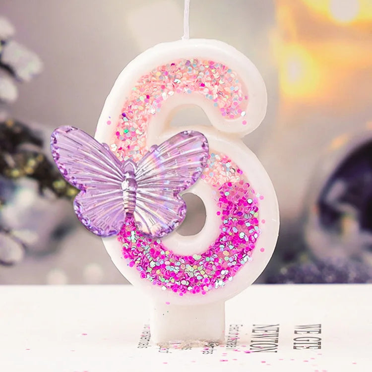 A white birthday candle shaped like the number 6 decorated with pink glitter and a purple butterfly
