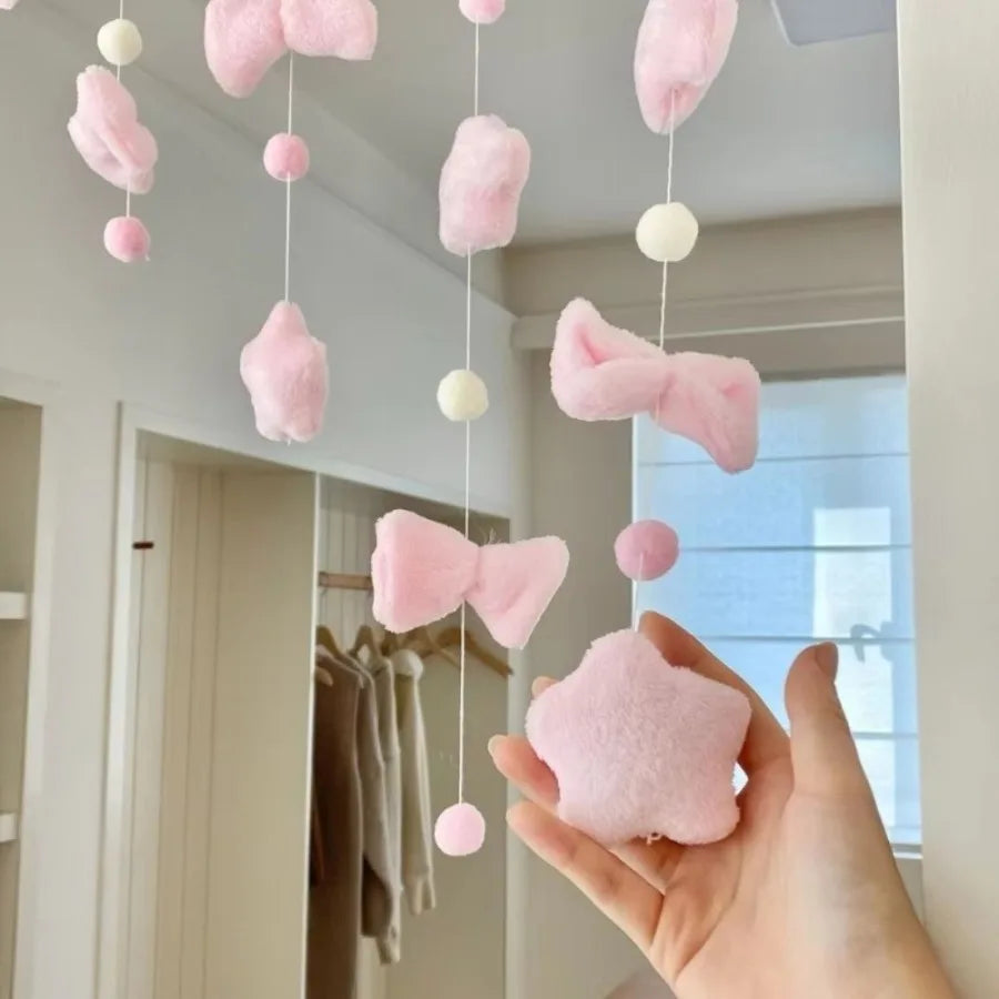 Pink tassel door curtain with heart and star decor hanging in front of a window.