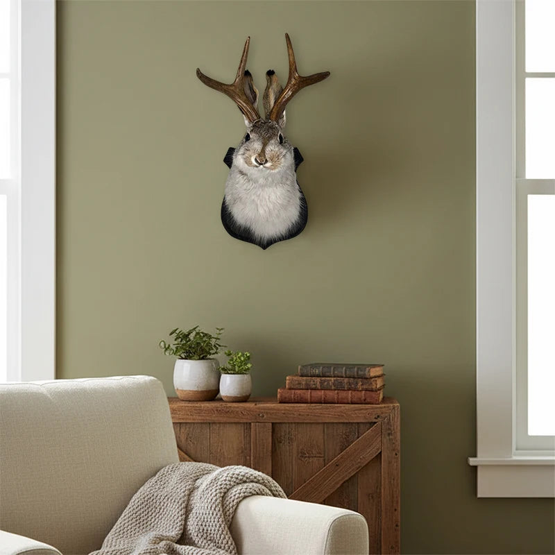 A decorative wall mount featuring a taxidermy bunny head with antlers mounted on a light green wall.