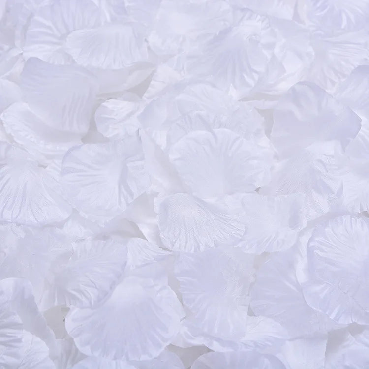 White artificial silk rose petals scattered on a surface.