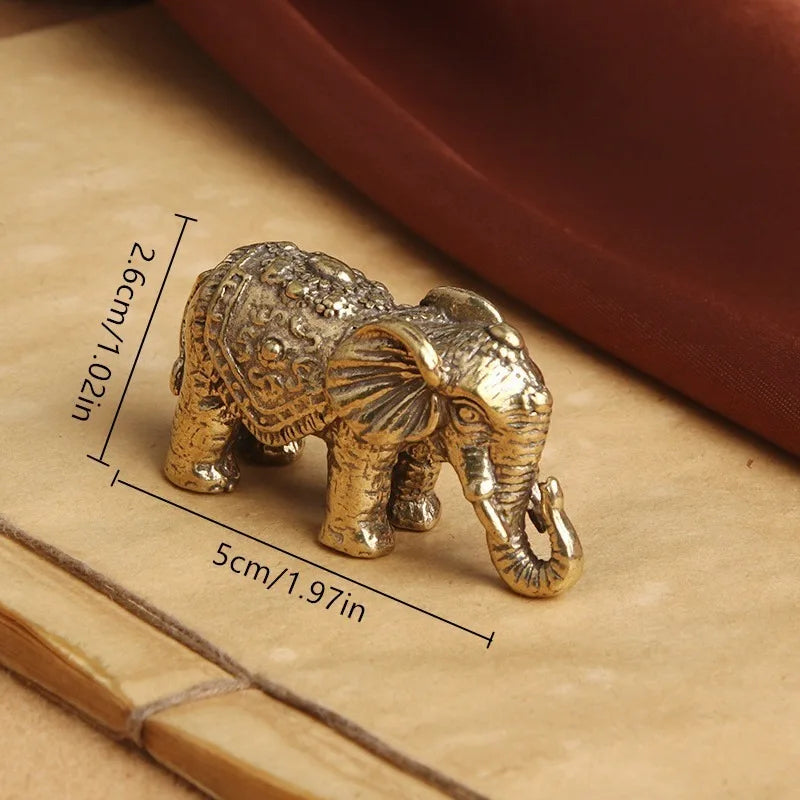 Antique bronze elephant figurine with a textured surface shown on a light brown background.
