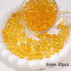 A clear glass dropper filled with round yellow spacer beads on a white dish.