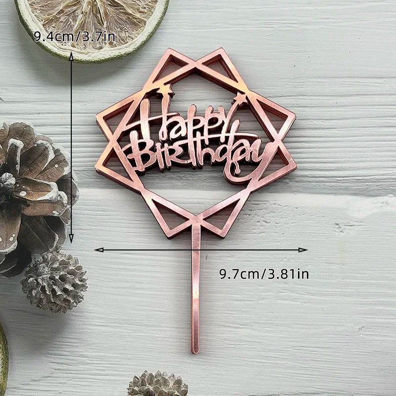 A rose gold acrylic birthday cake topper featuring the words Happy Birthday set against a light wooden background.