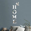A set of self-adhesive acrylic butterfly mirror wall stickers spelling out the word HOME on a gray wall.