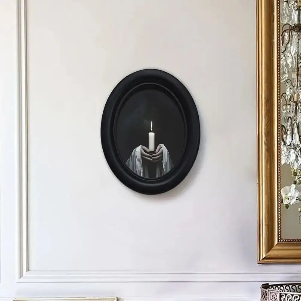 Black framed wooden wall art featuring a candlelit hand holding a flame