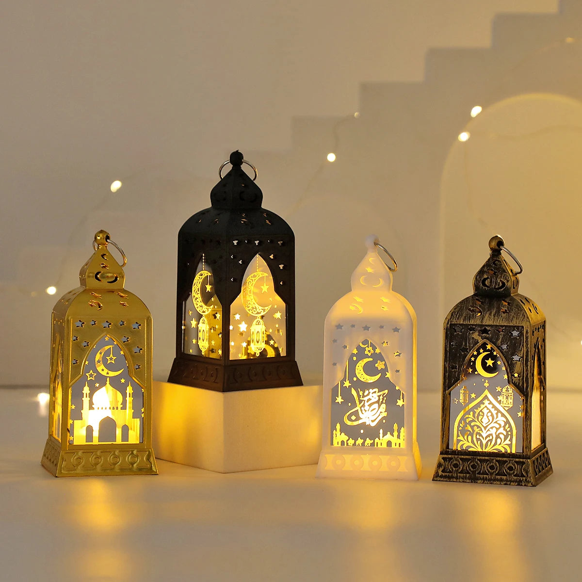 A collection of elegant LED star and moon lanterns glowing warmly on a white surface.