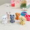 A collection of eight small, cute dog-shaped toys in various colors like white, pink, gray, orange, and yellow, displayed on 
