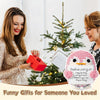 A handcrafted crochet penguin plush with an encouraging card is shown next to a woman in a festive holiday setting.