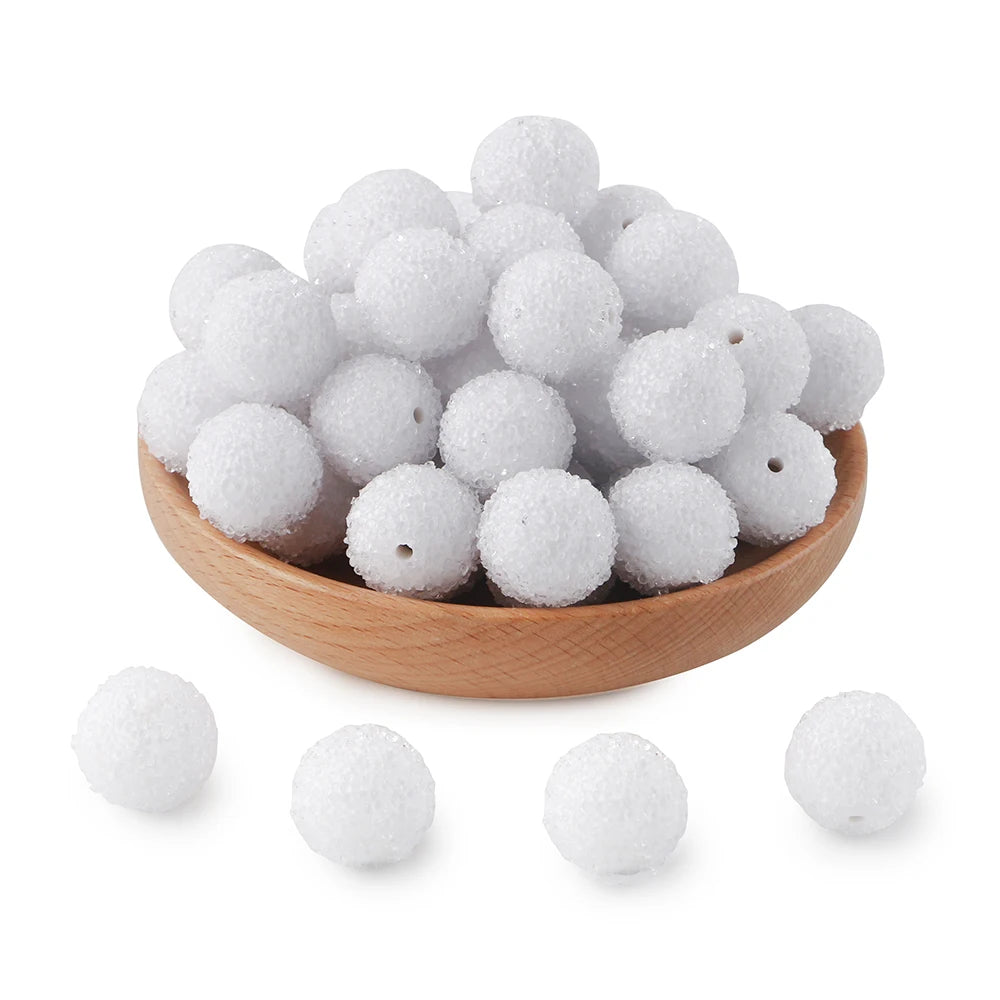 A pile of white textured resin beads for jewelry making in a wooden bowl and loose.