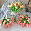 Un ramo de tulipanes artificiales rosas y amarillos dispuestos sobre tela blanca transparente.