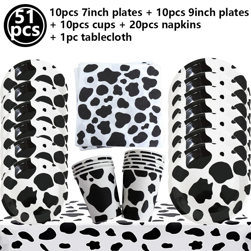 A set of cow print tableware including plates, cups, napkins, and a tablecloth for a farm-themed party.