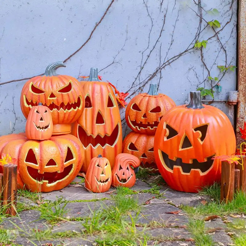 An arrangement of carved orange pumpkins with glowing LED lights displayed outdoors against a gray wall.