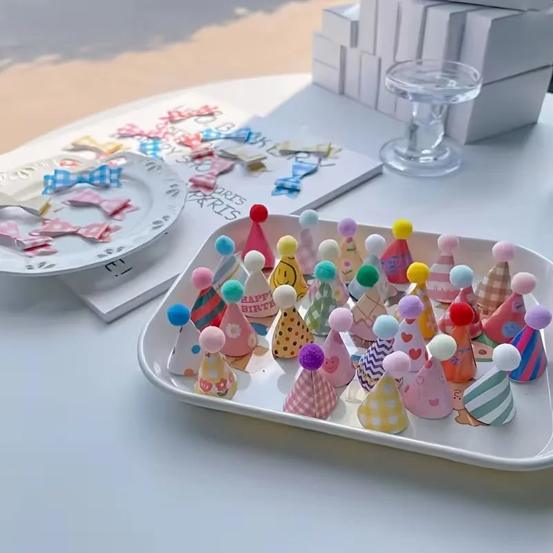 A white platter filled with mini colorful party hat cake toppers in various shades of pink, yellow, blue, and green.