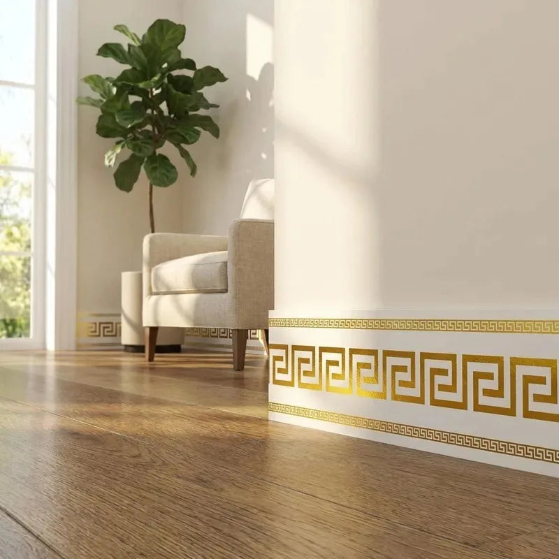Gold and white Greek key pattern self-adhesive PVC skirting board trim on a wooden floor.