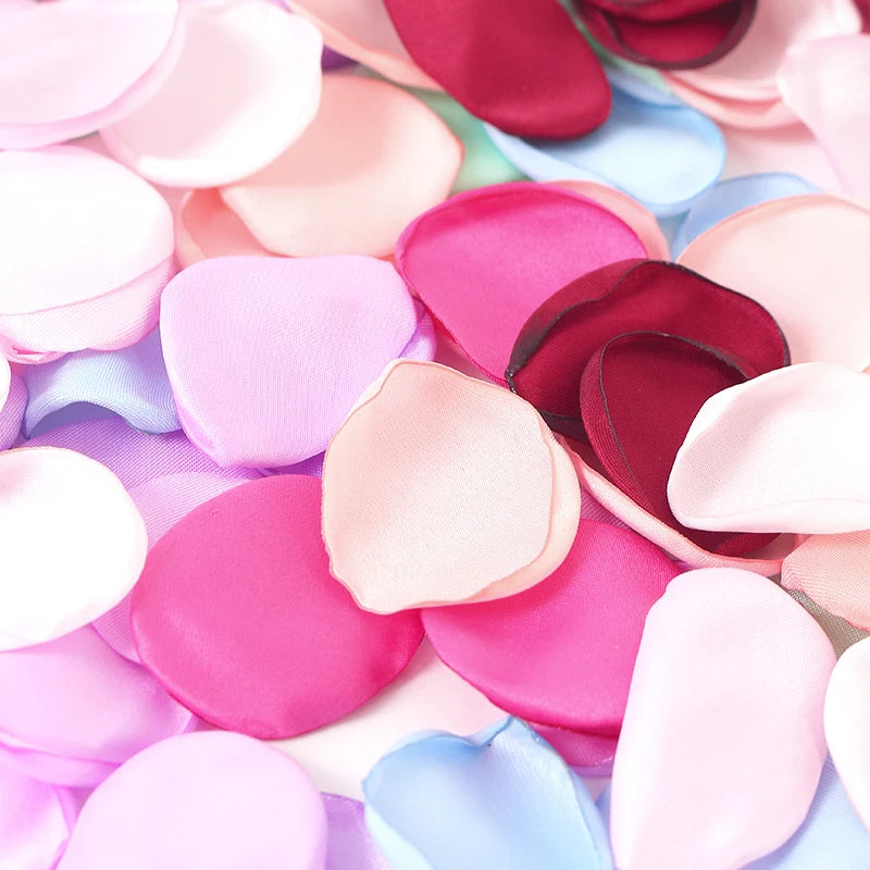 Primer plano de pétalos artificiales de flores rosas, moradas y azules esparcidos sobre una superficie.