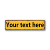 A rectangular vintage tin sign with distressed yellow paint and black text that reads Your text here.
