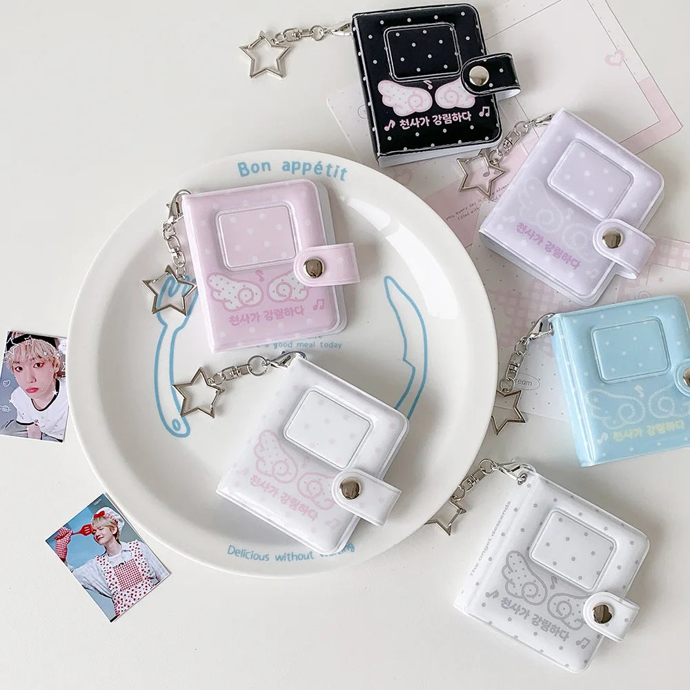 A collection of mini snap button photo albums in pink, white, and blue, featuring decorative elements and attached to silver 