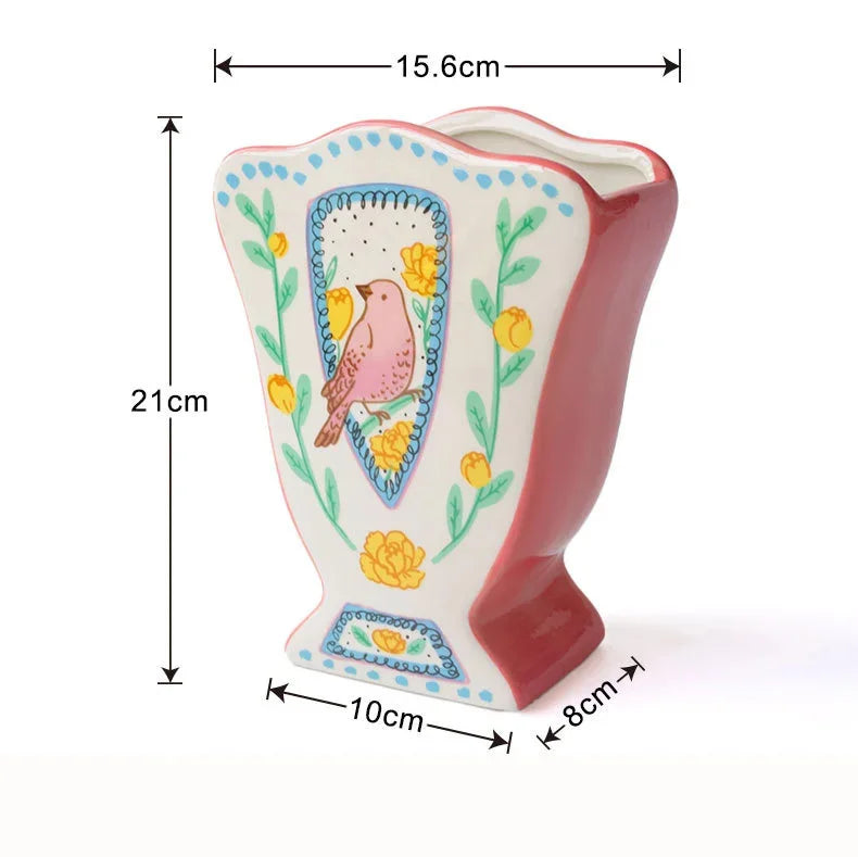 A pink ceramic vase with a floral design featuring a bird in a shield shape.