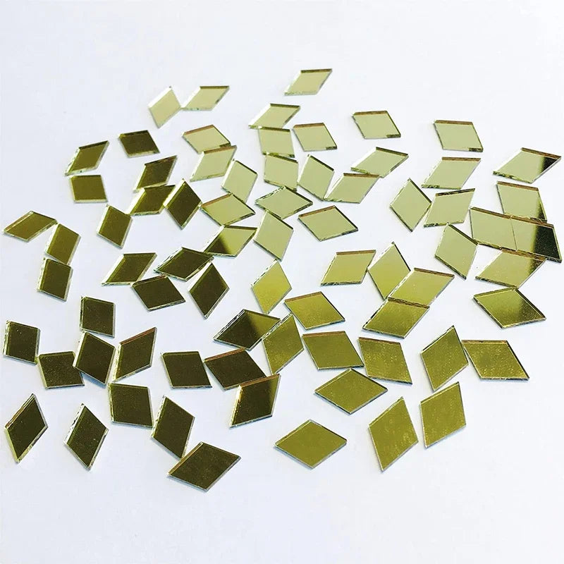 A scattered pile of small, square gold-colored mirror tiles used for 3D mosaic wall decals.