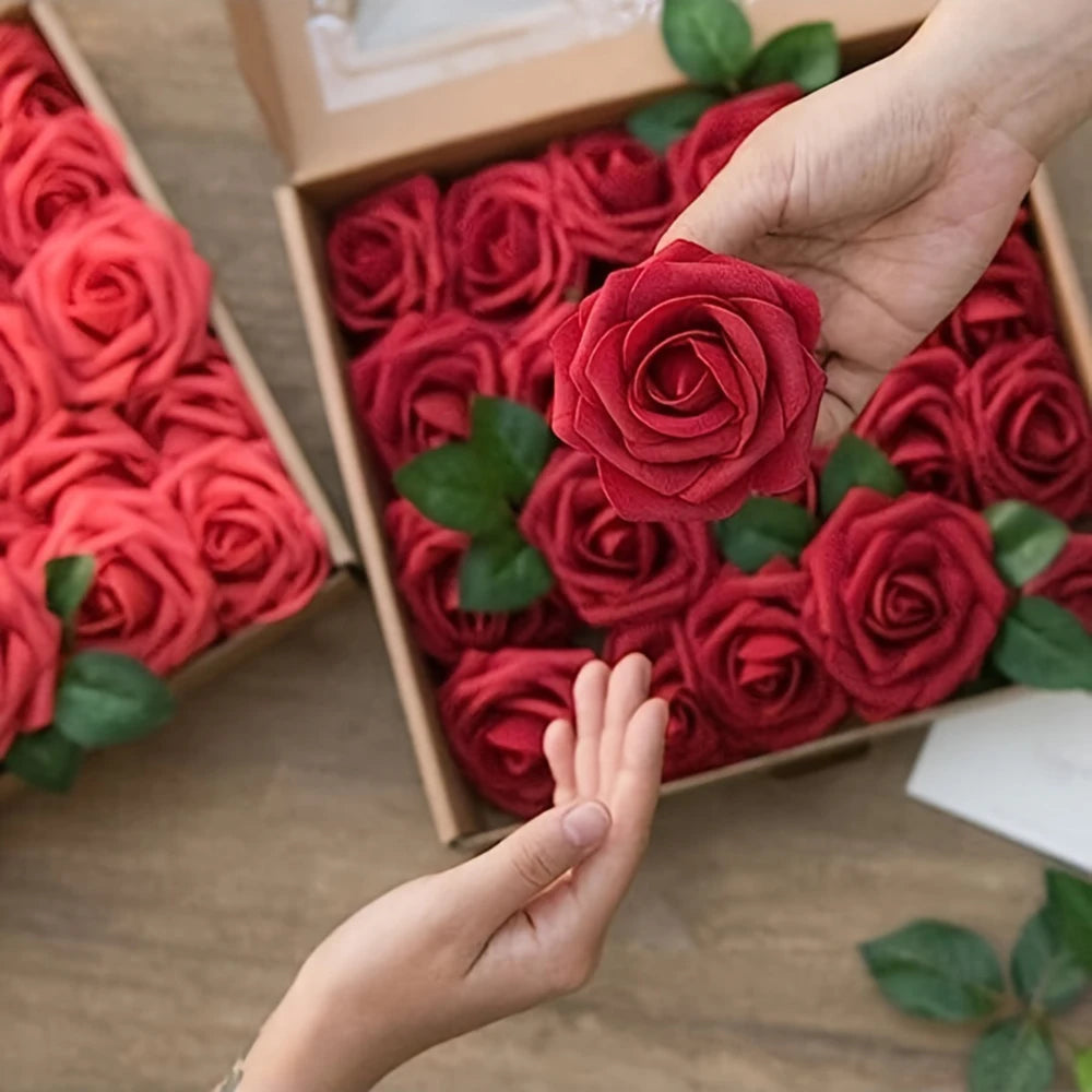 A hand places deep red artificial roses into a cardboard box for DIY decor.